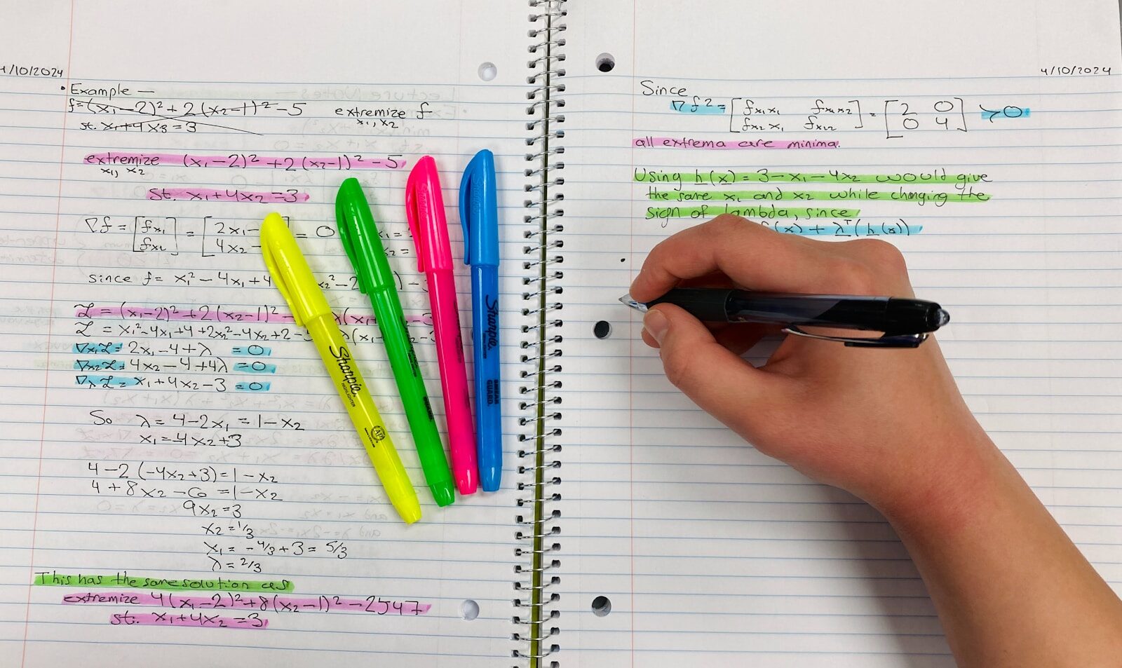 a person writing on a notebook with colored pens